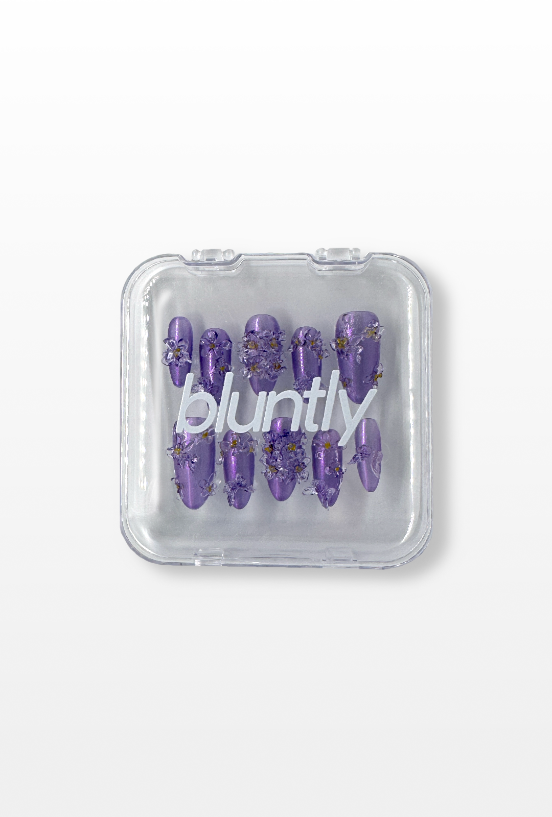 Set of purple nail tips in a clear 'bluntly' branded case on a light gray background